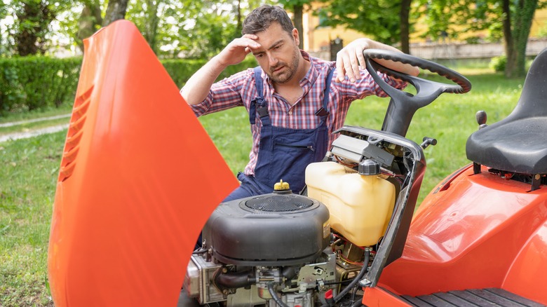 man with broken lawnmower