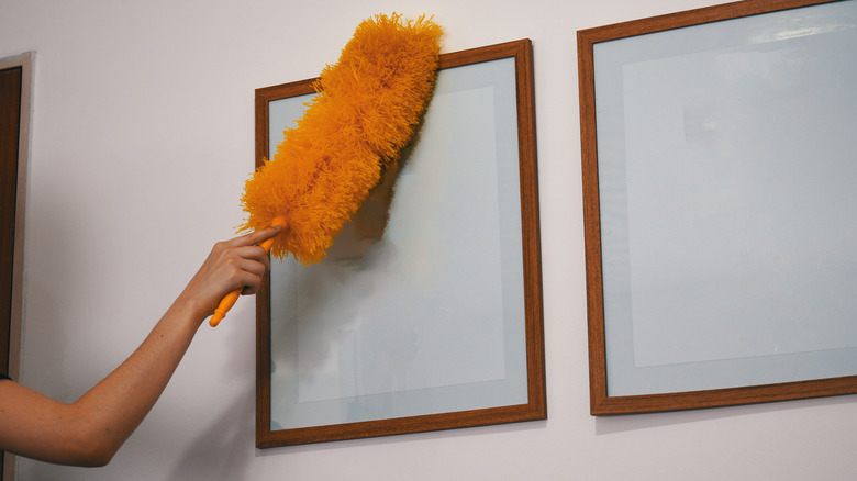 person dusting hanging frames