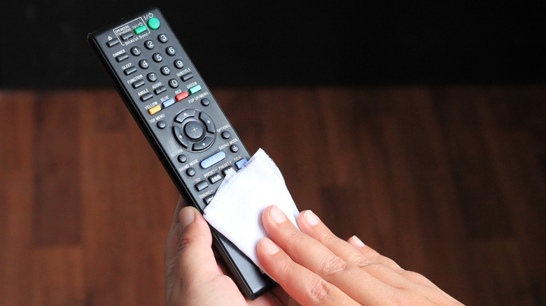 person cleaning black remote control