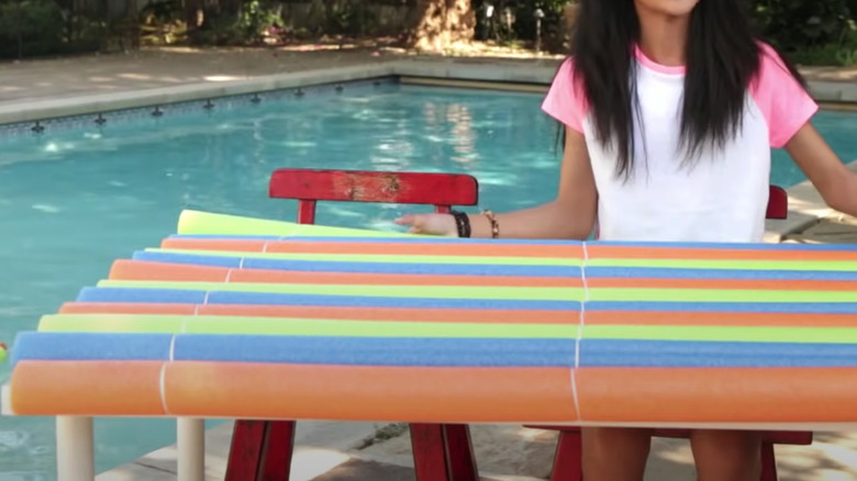 girl holding pool noodle raft