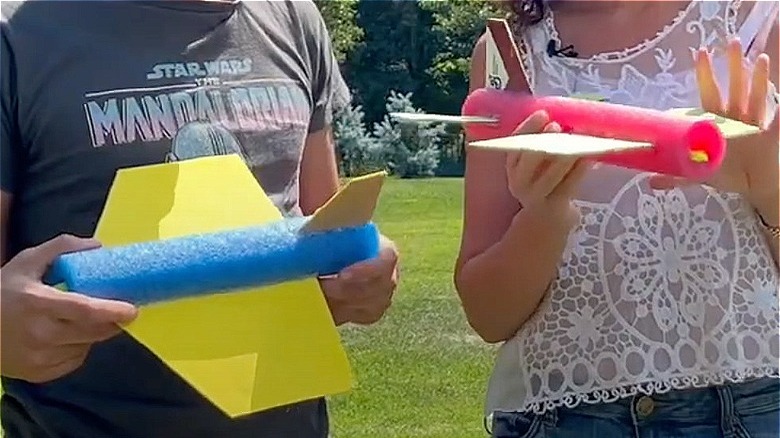 people holding pool noodle airplanes