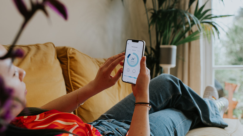 Woman controlling thermostat on phone