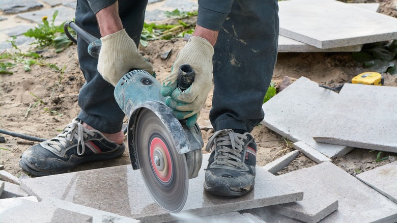 person cutting a paving stone