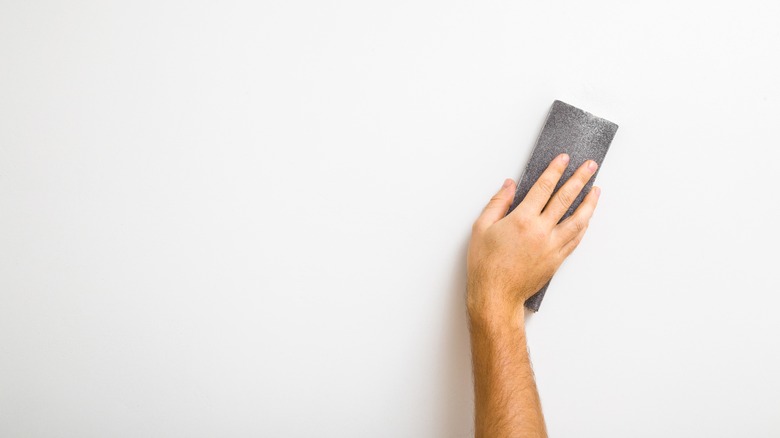 Person sanding walls for painting