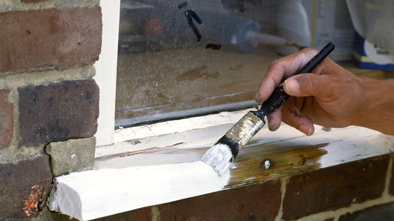 Person painting window trim