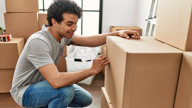 man writing on cardboard box