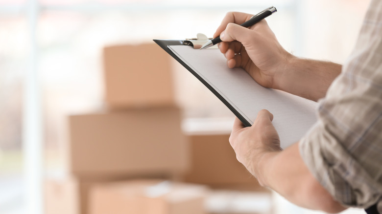 man writing on clipboard