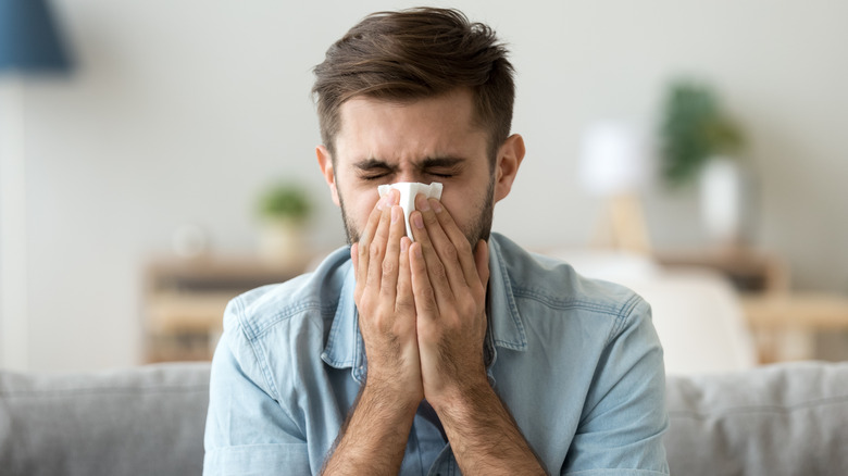 man blowing nose at home