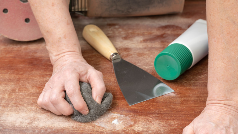 carpenter smoothing filled wood hole