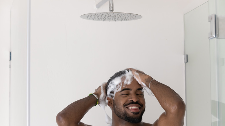 man bathing under large showehead
