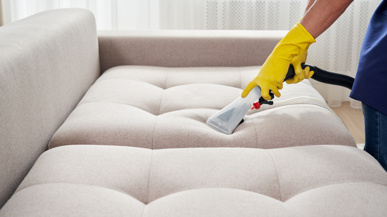 vacuuming a light beige couch