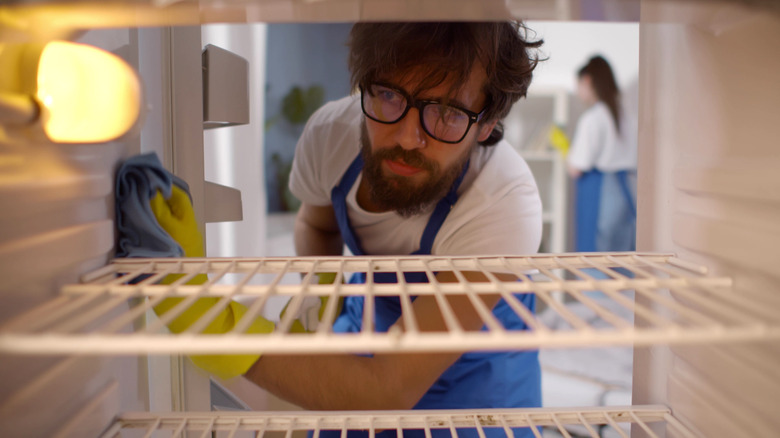 man cleaning a fridge