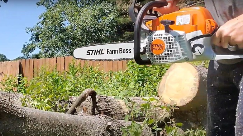 Man cutting wood with a Stihl Farm Boss chainsaw