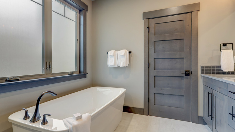 Bathroom with dark gray door and freestanding tub