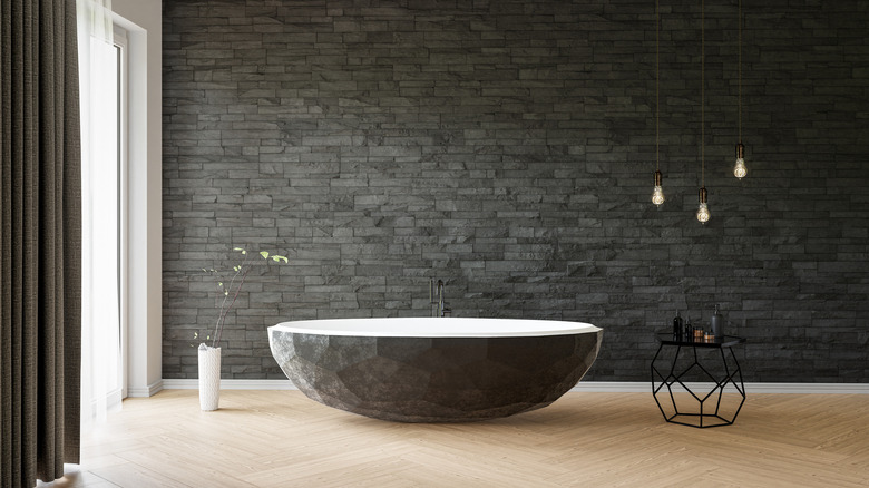 Dark gray bathroom with stone wall and tub