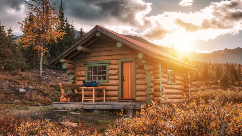 sun setting behind a cabin