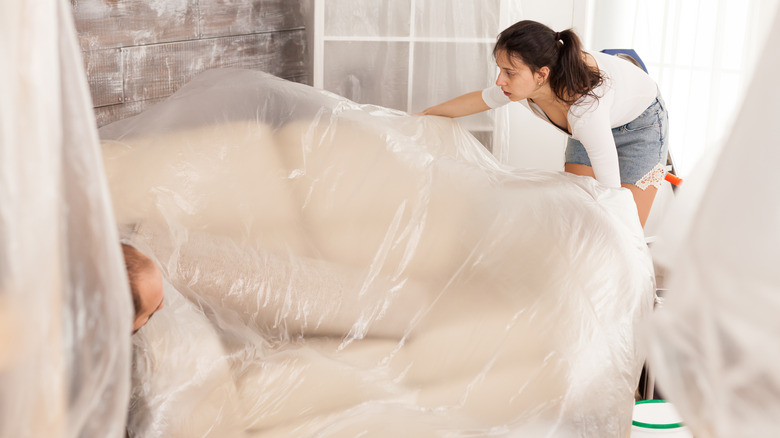 people covering couch in plastic