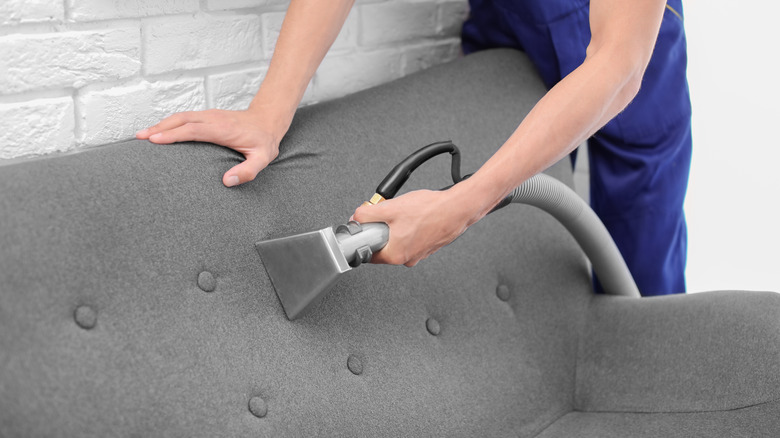 Male Worker Cleaning Sofa With Vacuum Cleaner Stock Photo