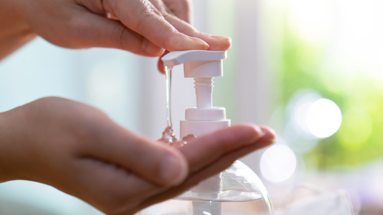 Close up view of hands using a liquid hand soap dispenser