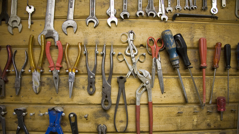 Various small tools hanging on wooden wall