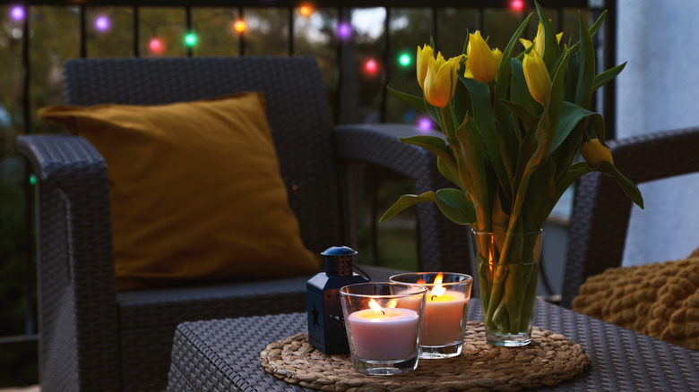 Wicker patio table with lit candles and vase of tulips