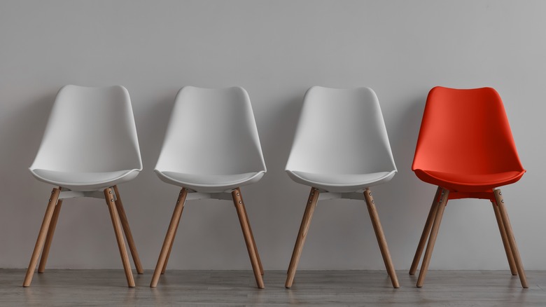 three white chairs and one red chair