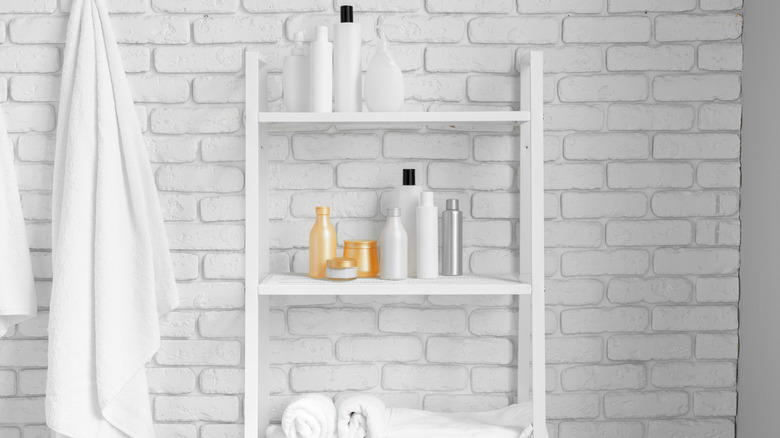 Tall bathroom storage shelf on white brick wall