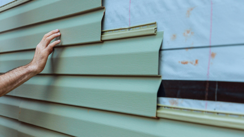 A hand works on installing vinyl panels