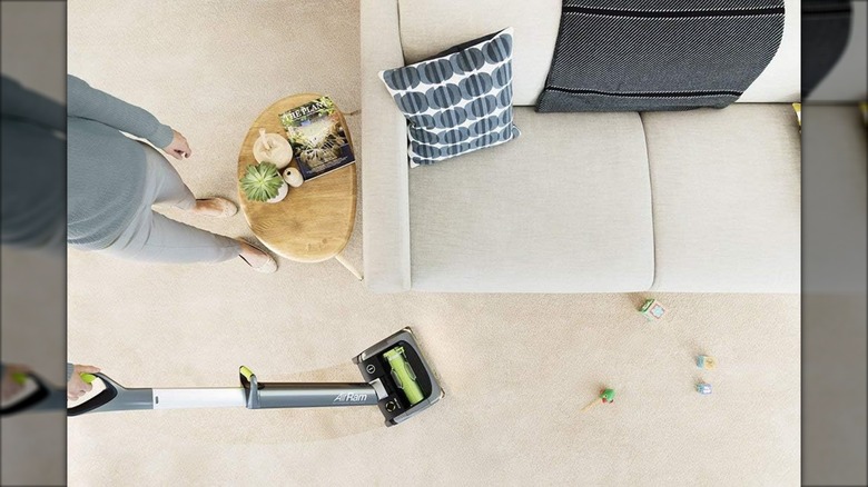 A Bissell vacuum is used near a beige couch