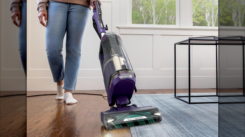 A person uses a Shark Power Detect vacuum