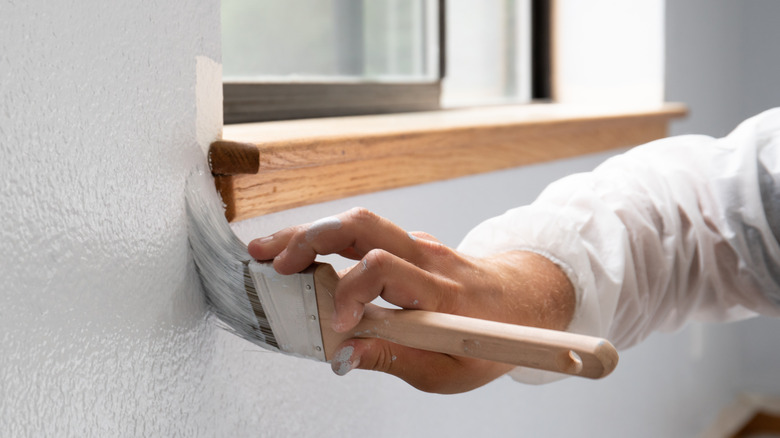 person painting edge of window sill 