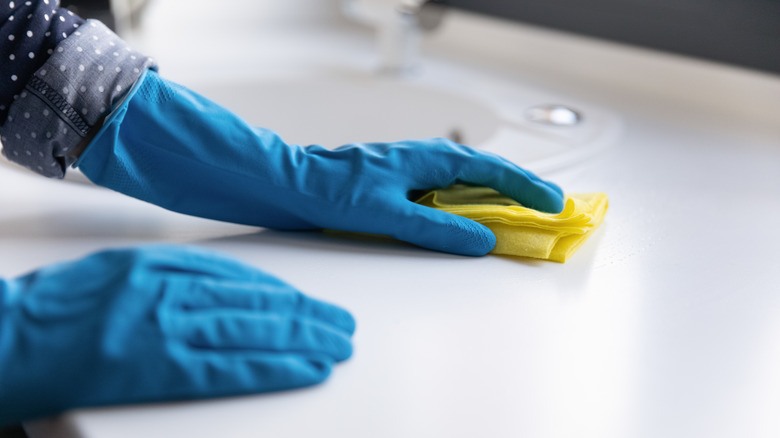 person wipes countertop with rag