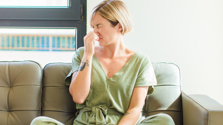 Woman hold nose on furniture