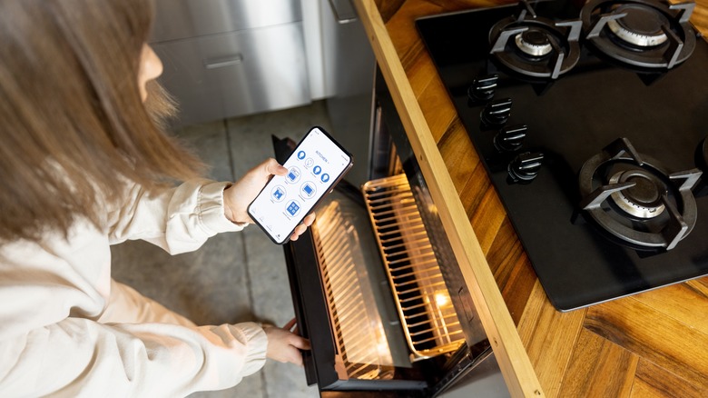 woman controlling oven with phone