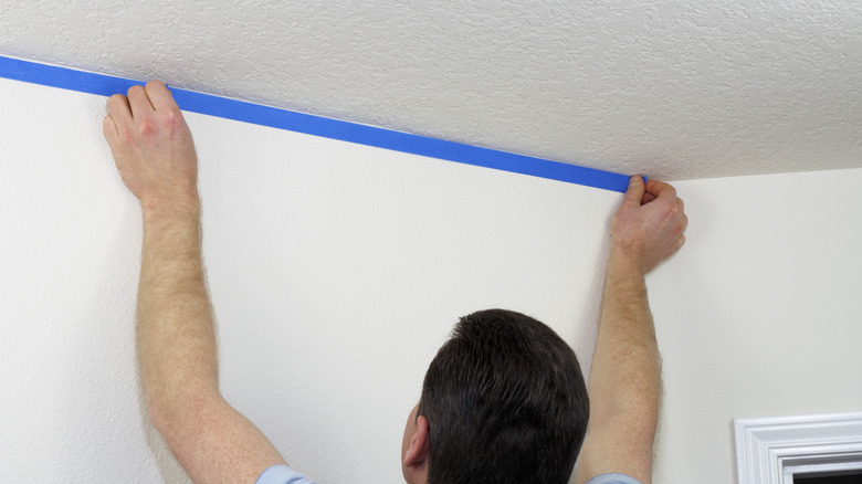 Man tapes edges of ceiling