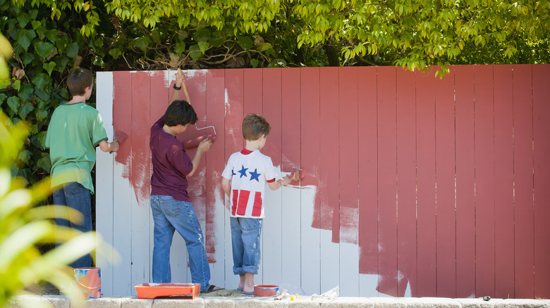 Boys painting wooden fence