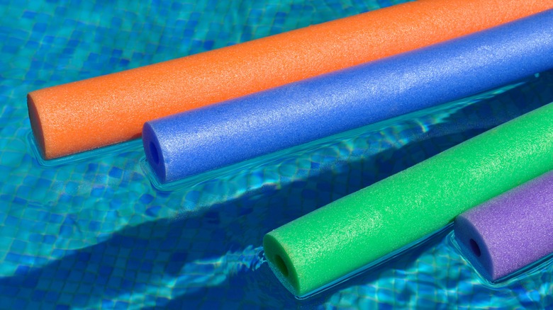 Orange, blue, green, and purple noodles in a pool