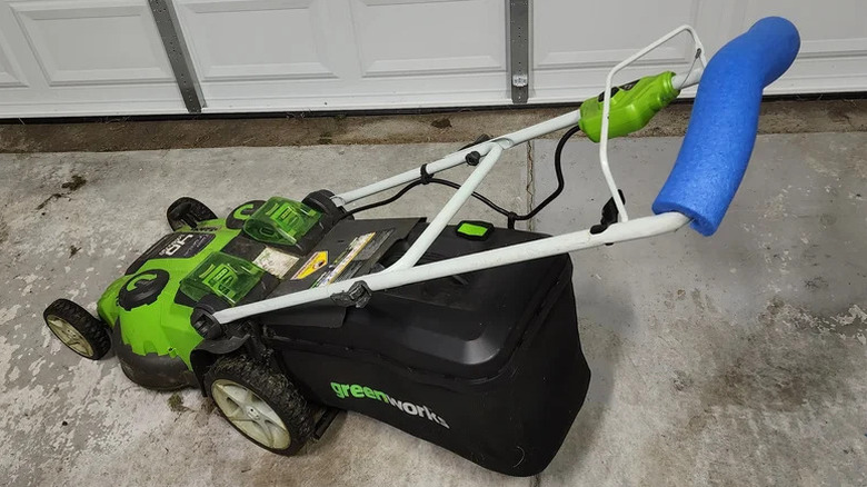 Push mower with section of blue pool noodle over handle