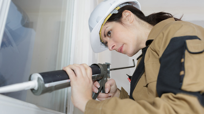 Person caulking a window