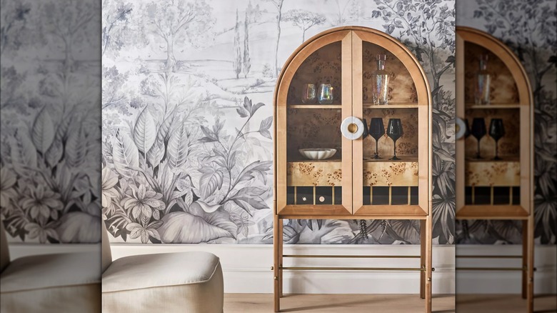 A stylish drink cabinet sits in front of a neutral wallpaper mural