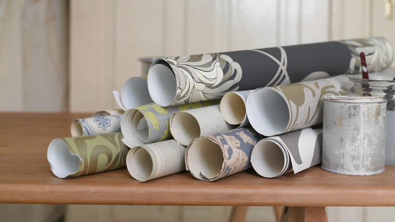 Rolls of wallpaper sit on a wooden table