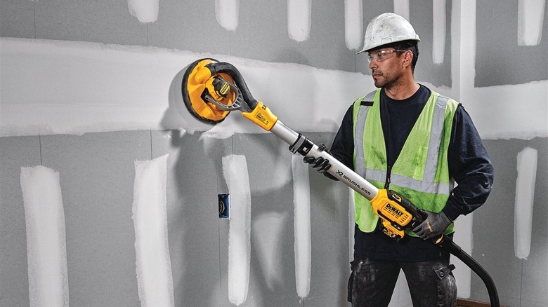 A man uses a DeWalt drywall sander