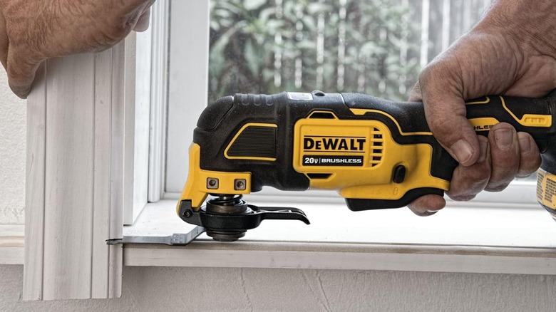 A man uses the DeWalt brushless multitool to cut window trim