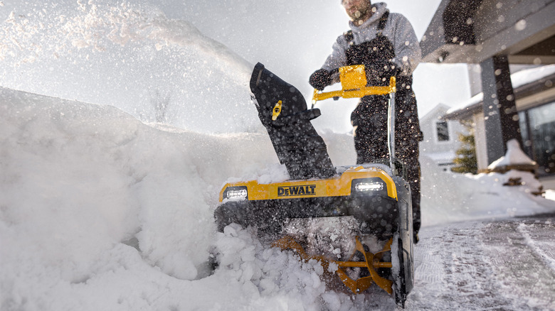 A man uses a DeWalt snow blower to clear a path