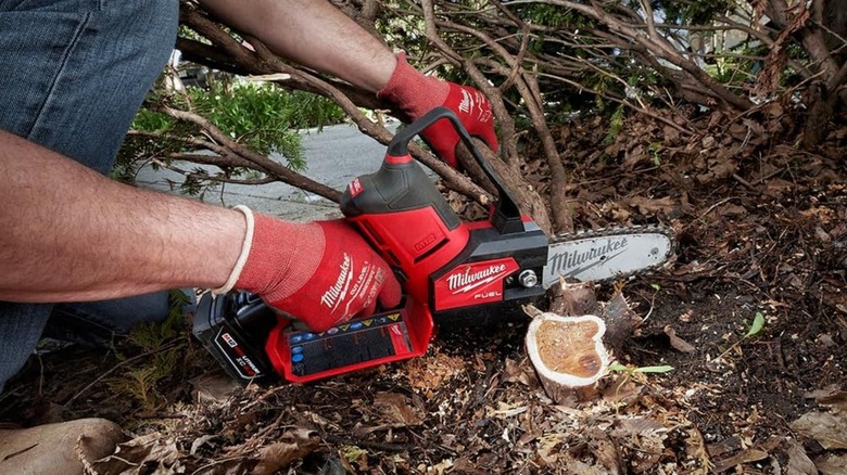 Man cutting through a tree limb with Milwaukee pruning saw