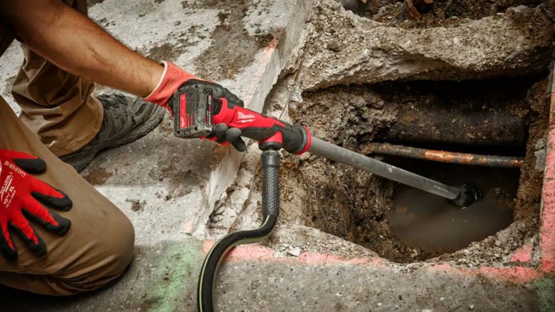 Man using transfer pump to drain a hole in concrete