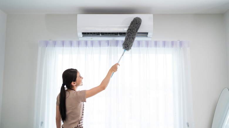 Woman dusting AC unit 