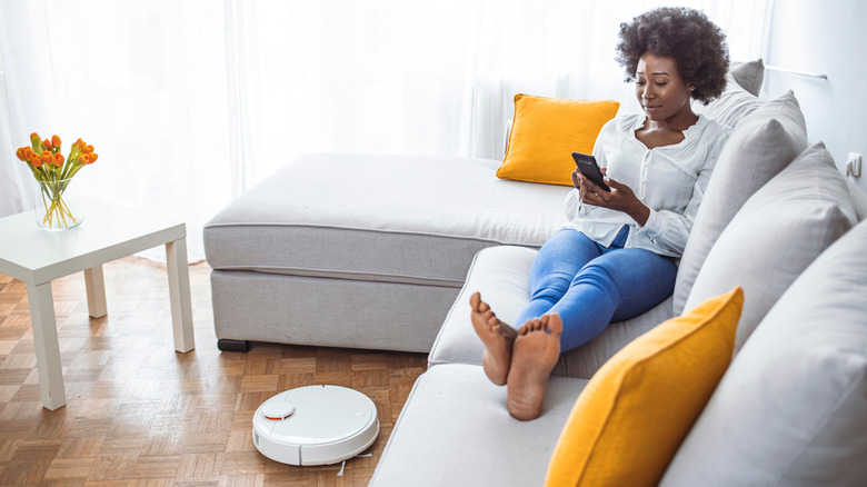 Woman relaxing while robot vacuums 