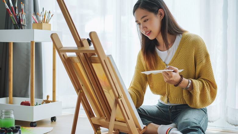 woman painting canvas on easel