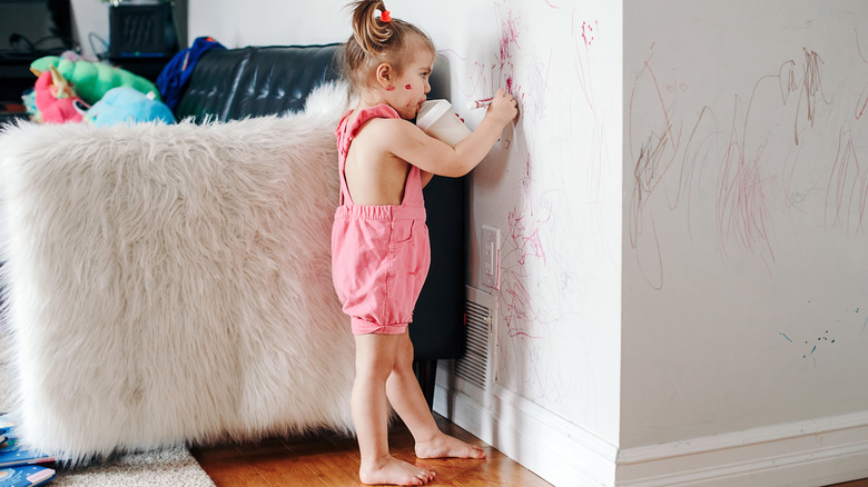 young girl drawing on wall